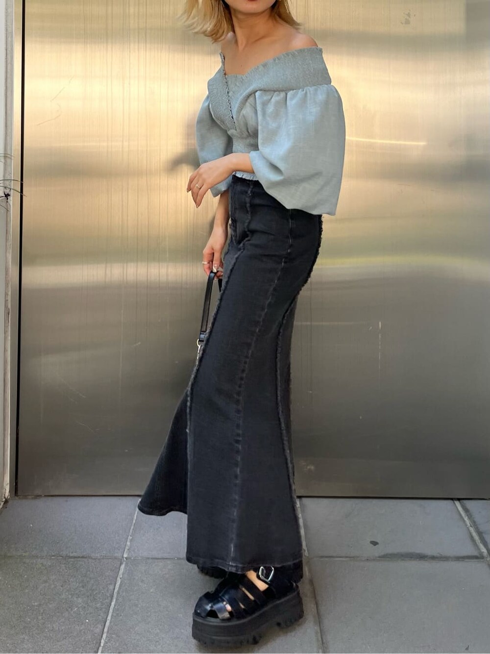 ブラック系のハンドバッグ、ブルー系のスカート、ブルー系のシャツ/ブラウスを着用したレディースの夏コーディネートの6枚目の写真