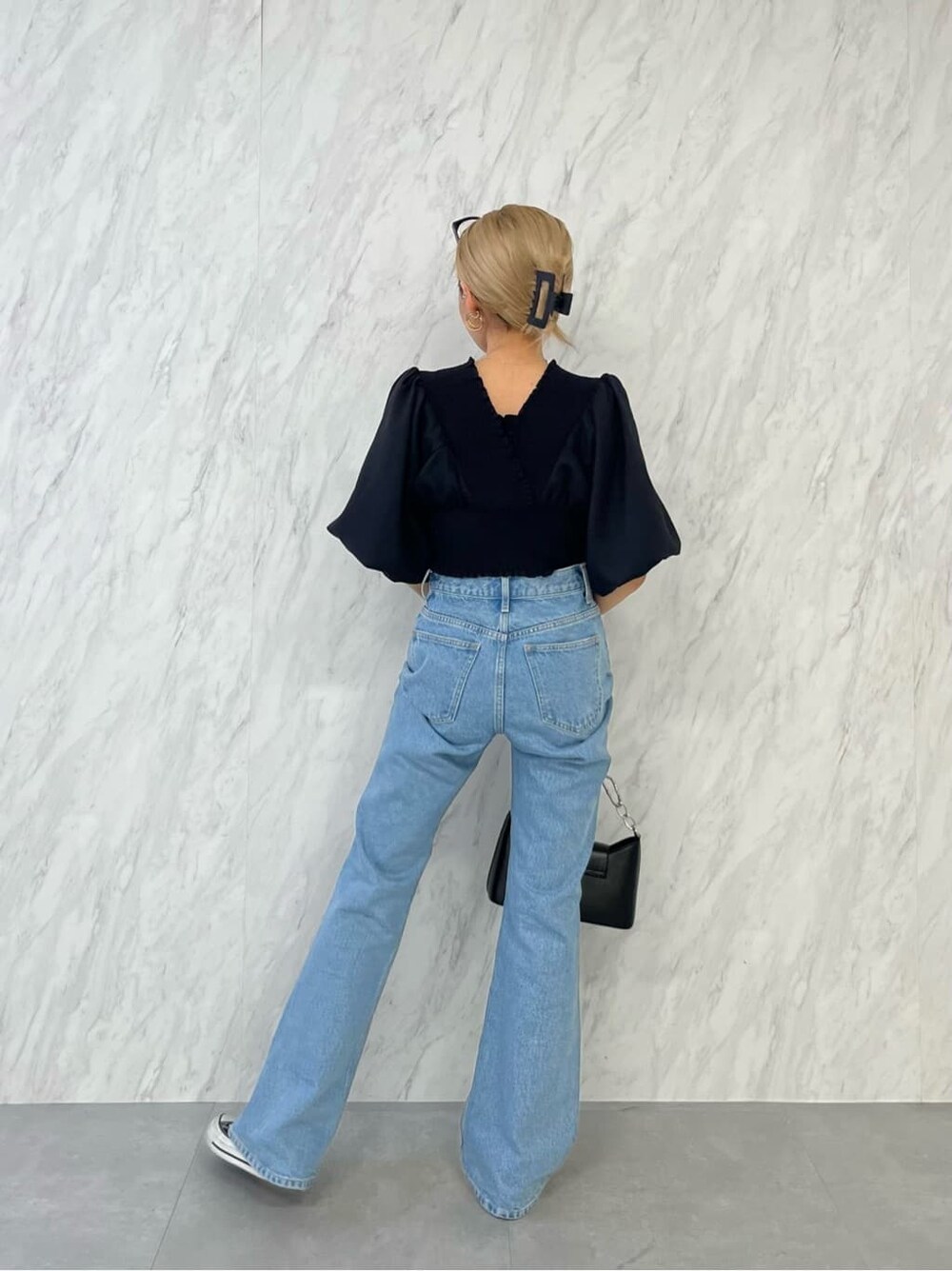 ブラック系のシャツ/ブラウス、ブラック系のハンドバッグ、ブルー系のデニムパンツを着用したレディースの春コーディネートの4枚目の写真