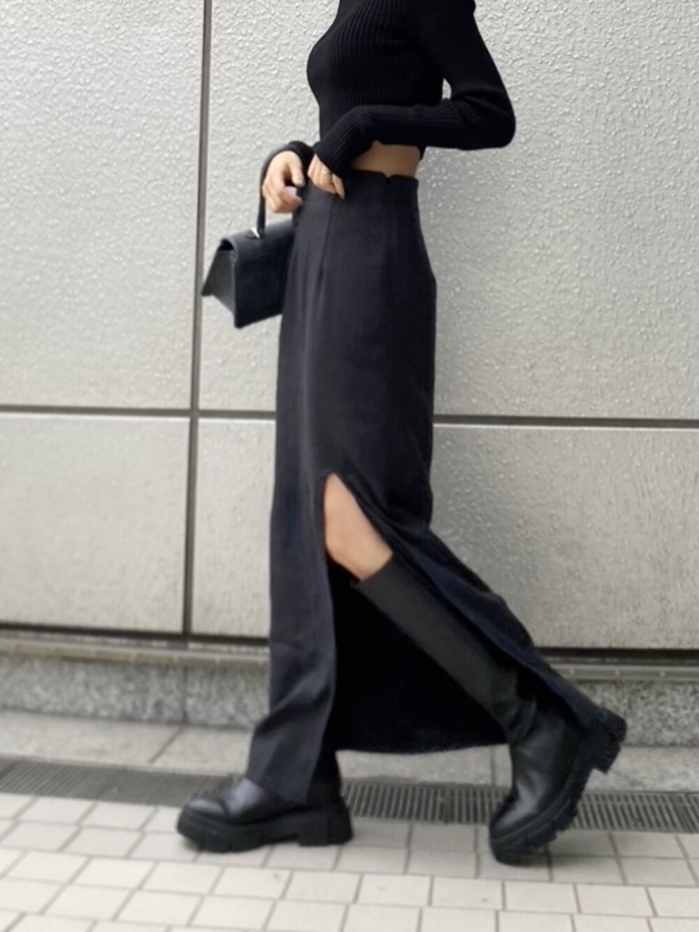 ブラック系のニット/セーター、ブラック系のブーツ、ブラック系のハンドバッグを着用したレディースの冬コーディネートの4枚目の写真