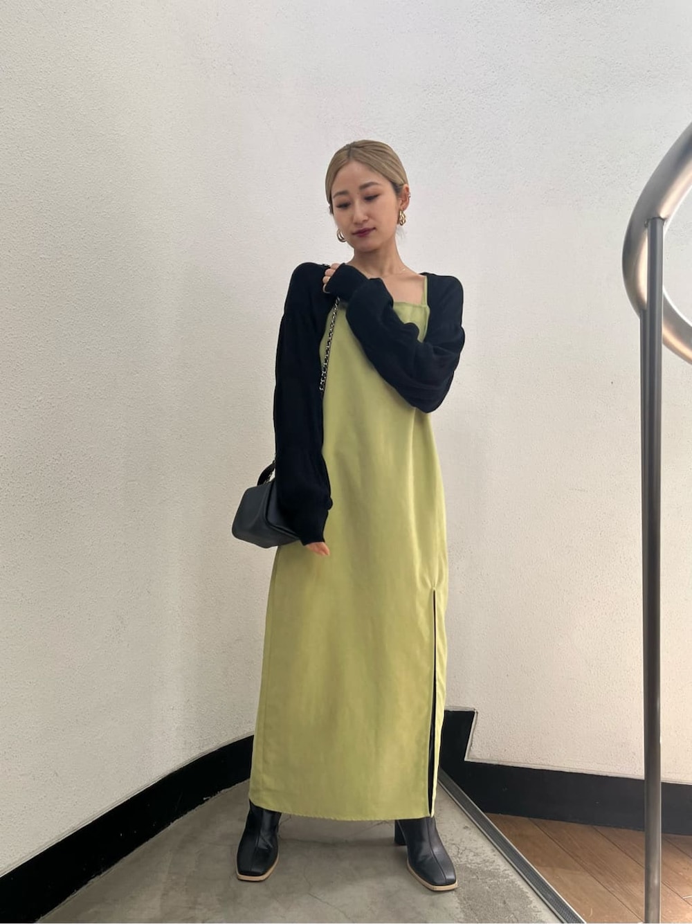 ブラック系のブーツ、ブラック系のニット/セーター、イエロー系のワンピースを着用したレディースの春コーディネートの3枚目の写真