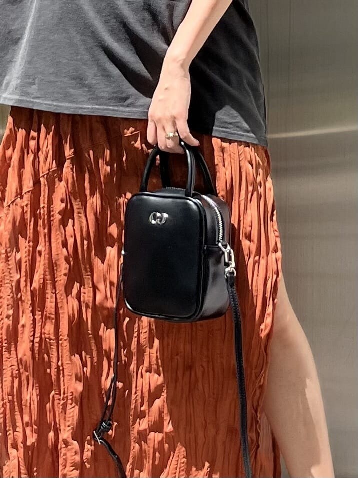 ブラック系のショルダーバッグ、オレンジ系のワンピース、ブラック系のサンダルを着用したレディースの春コーディネートの7枚目の写真