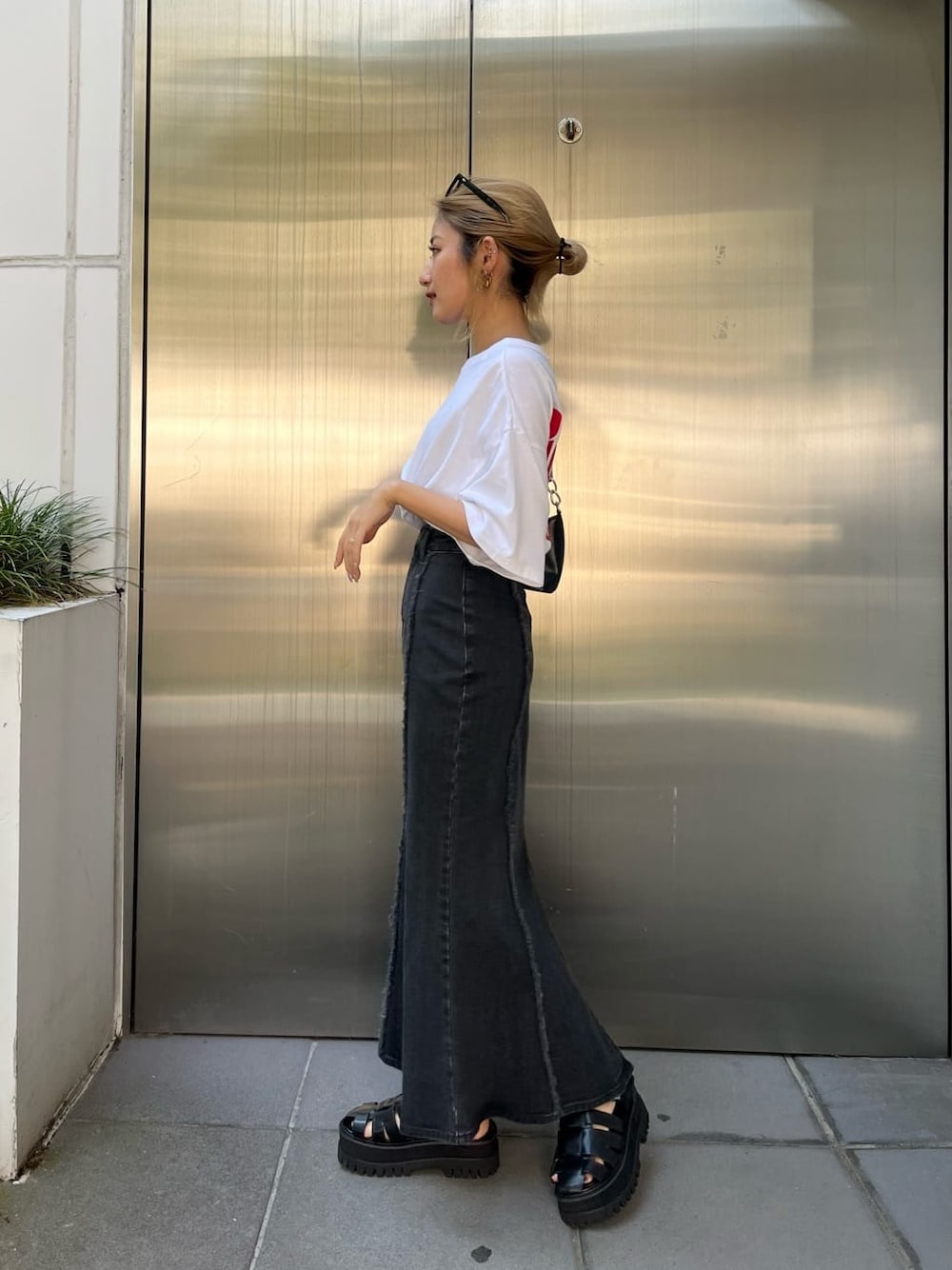 ブラック系のハンドバッグ、ブラック系のスカート、ホワイト系のTシャツ/カットソーを着用したレディースの夏コーディネートの2枚目の写真