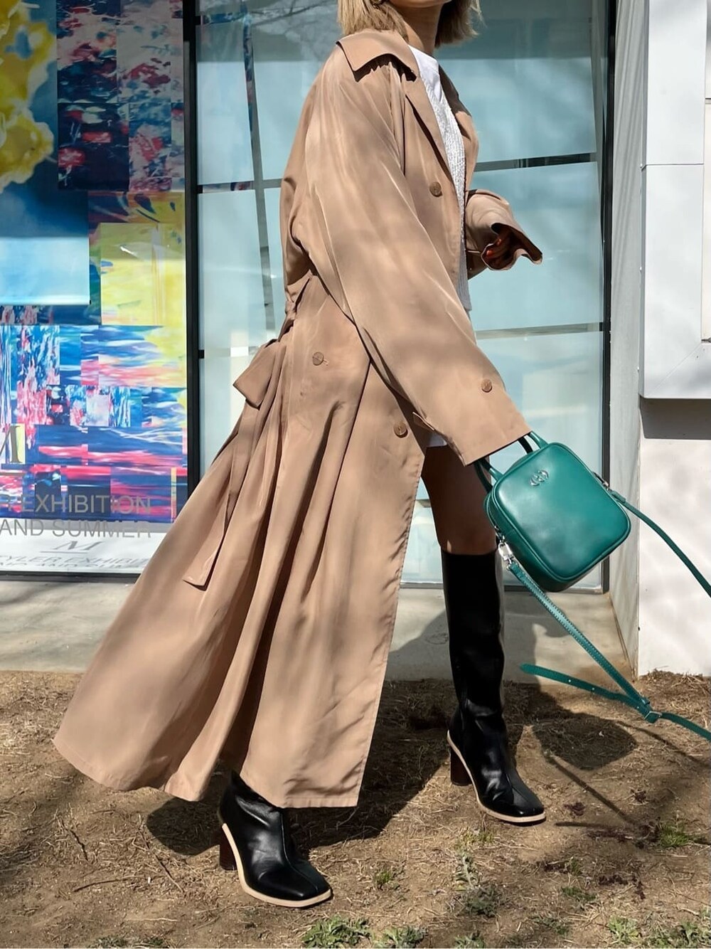 ブラック系のブーツ、ホワイト系のTシャツ/カットソー、ベージュ系のトレンチコートを着用したレディースの春コーディネートの3枚目の写真