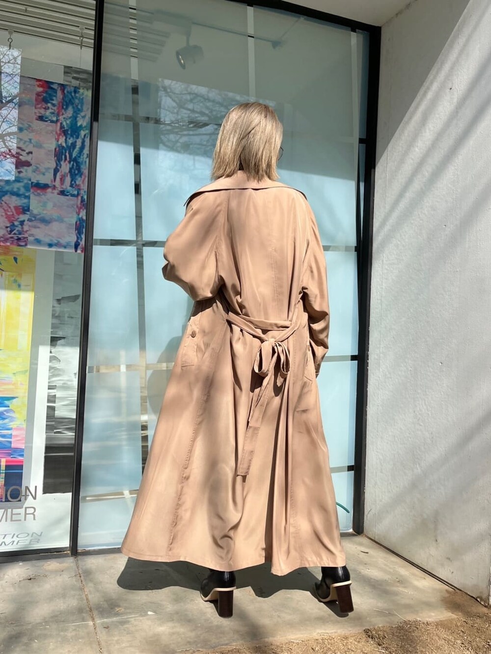 ブラック系のブーツ、ホワイト系のTシャツ/カットソー、ベージュ系のトレンチコートを着用したレディースの春コーディネートの2枚目の写真