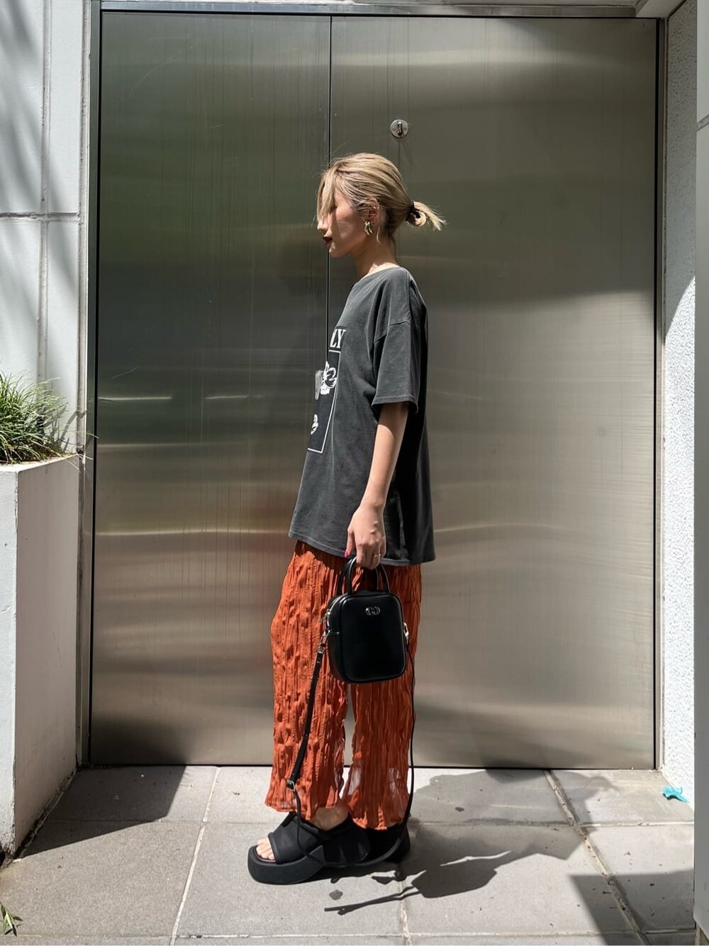 ブラック系のショルダーバッグ、オレンジ系のワンピース、ブラック系のサンダルを着用したレディースの春コーディネートの3枚目の写真