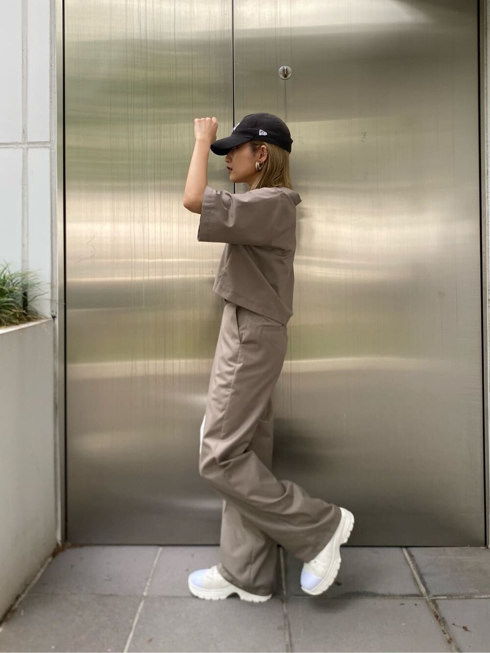 ホワイト系のスニーカー、ブラック系のハンドバッグを着用したレディースの春コーディネートの3枚目の写真