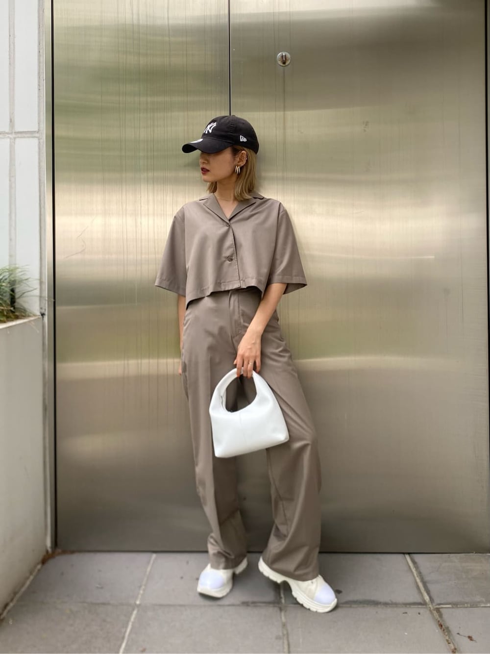 ホワイト系のスニーカー、ブラック系のハンドバッグを着用したレディースの春コーディネートの2枚目の写真