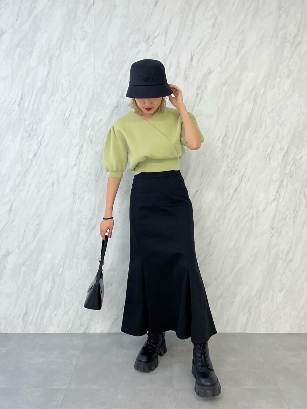 ブラック系のブーツ、ブラック系のスカート、イエロー系のニット/セーターを着用したレディースの春コーディネートの3枚目の写真