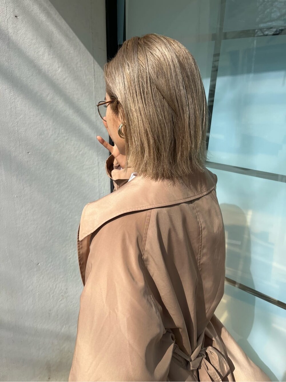 ブラック系のブーツ、ホワイト系のTシャツ/カットソー、ベージュ系のトレンチコートを着用したレディースの春コーディネートの6枚目の写真