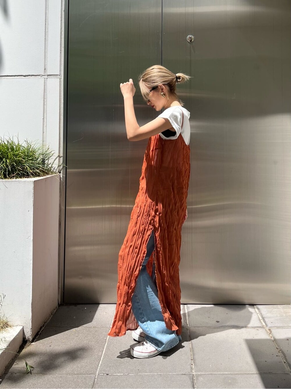 オレンジ系のワンピース、ブルー系のデニムパンツを着用したレディースの春コーディネートの3枚目の写真