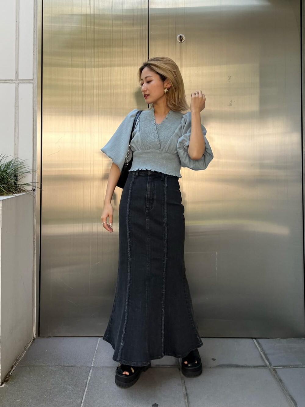 ブラック系のハンドバッグ、ブルー系のスカート、ブルー系のシャツ/ブラウスを着用したレディースの夏コーディネートの2枚目の写真