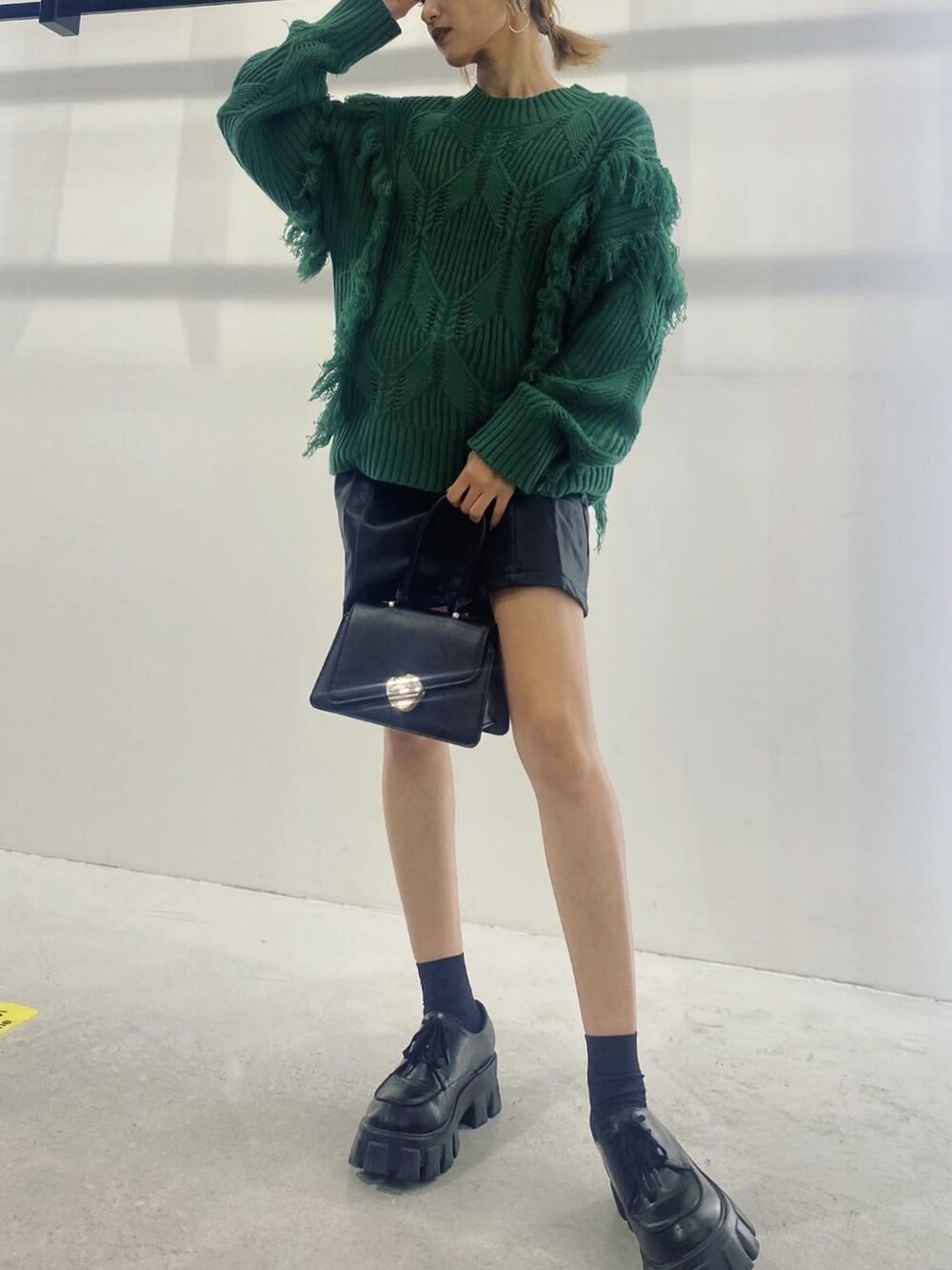 グリーン系のニット/セーター、ブラック系のハンドバッグ、ブラック系のワンピースを着用したレディースの秋コーディネートの2枚目の写真