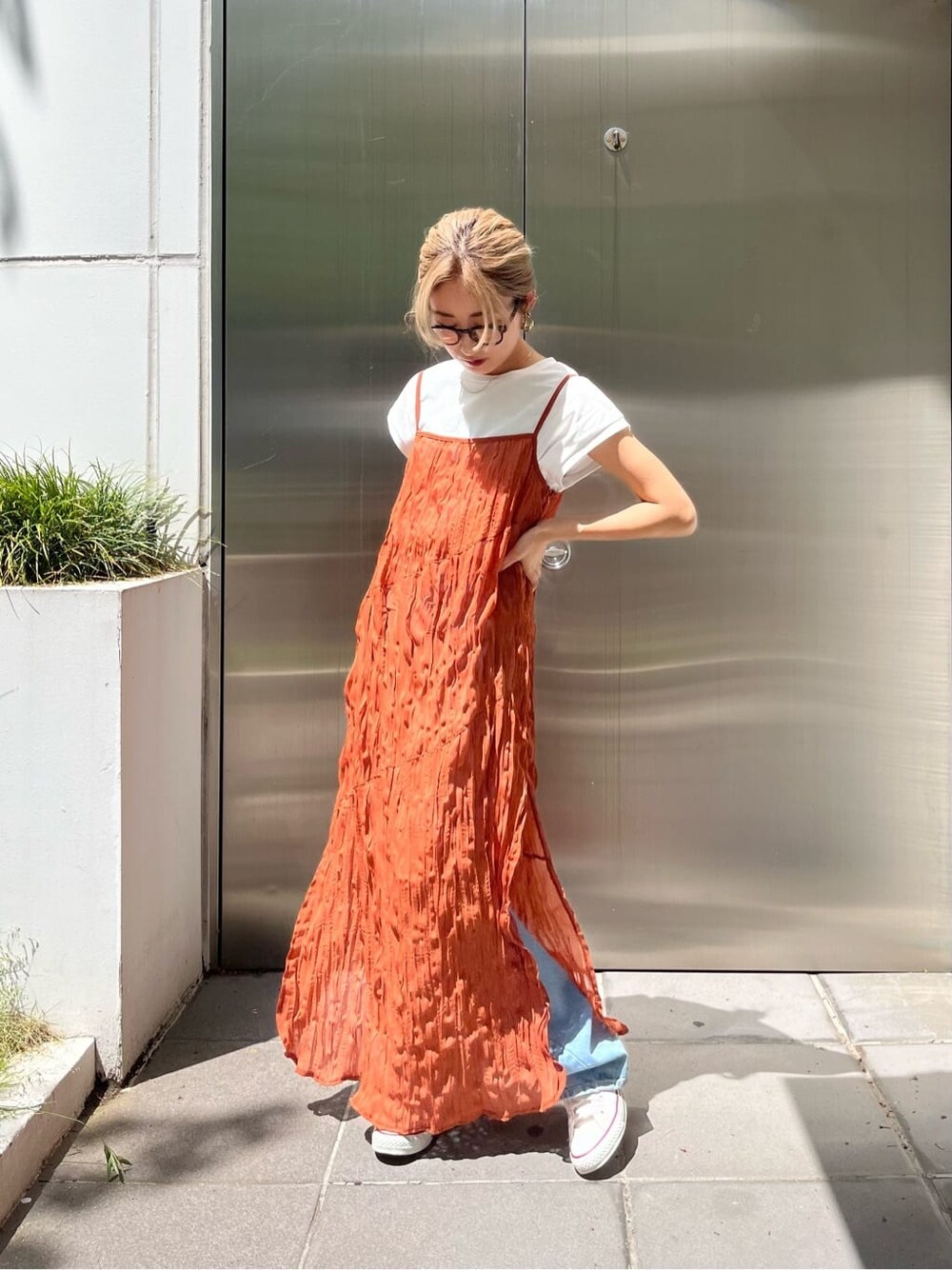 オレンジ系のワンピース、ブルー系のデニムパンツを着用したレディースの春コーディネートの2枚目の写真