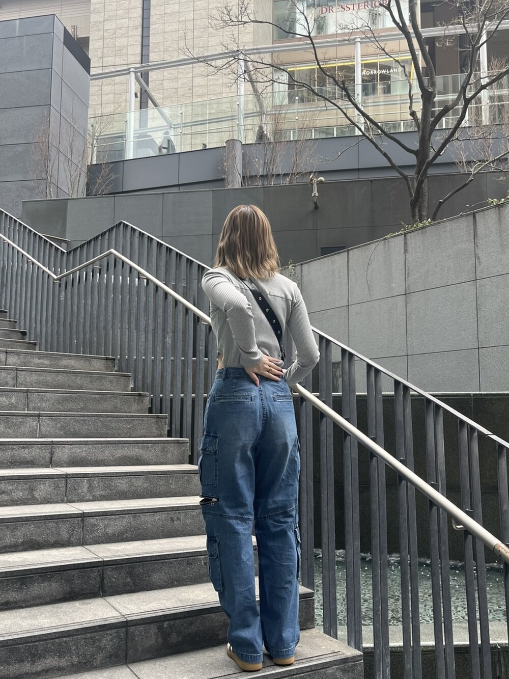 ブルー系のデニムパンツ、グレー系のTシャツ/カットソー、ブラック系のショルダーバッグを着用したレディースの春コーディネートの2枚目の写真