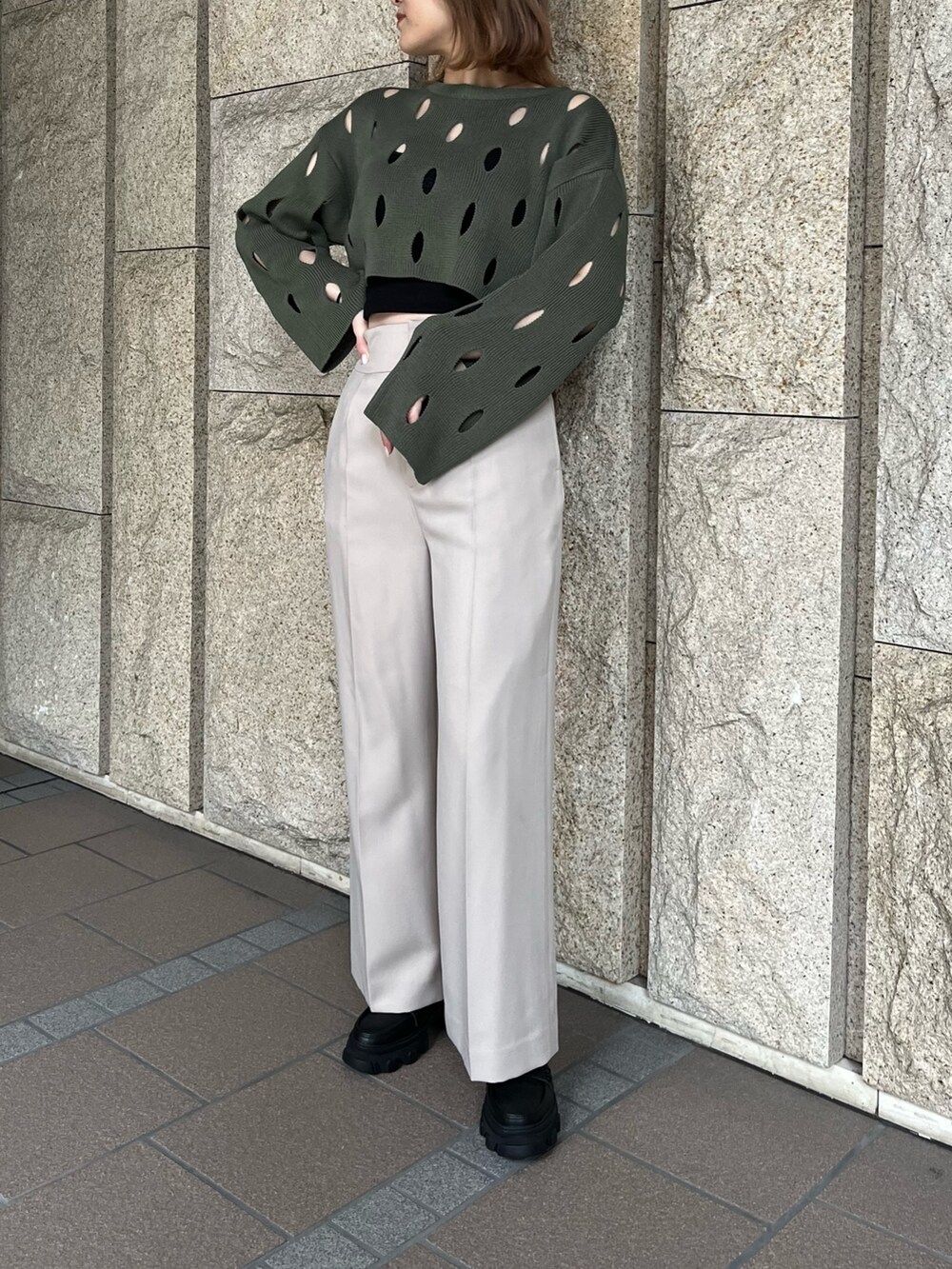 ブラック系のローファー、ベージュ系のスラックス、グリーン系のニット/セーターを着用したレディースの冬コーディネートの2枚目の写真