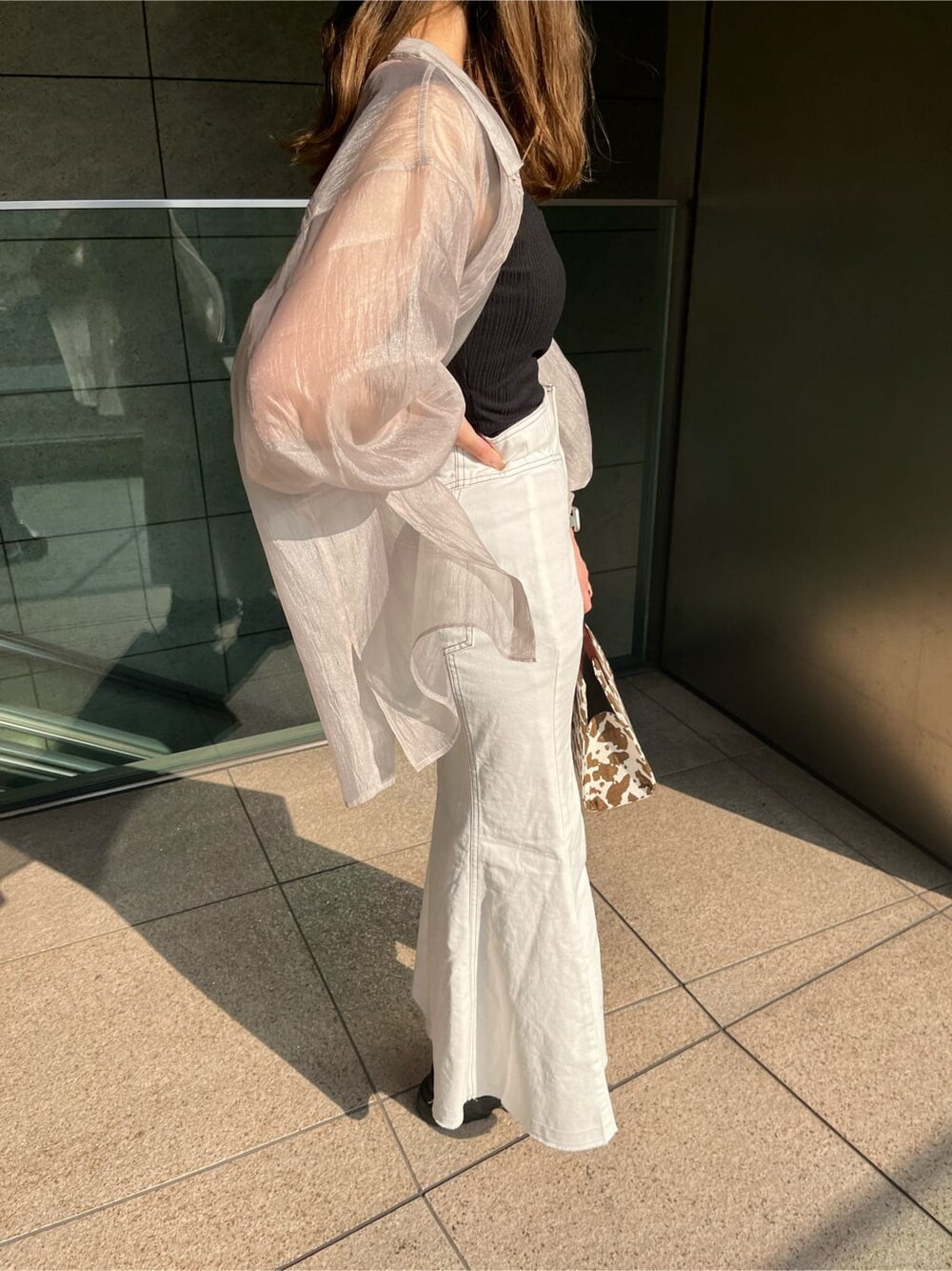 ブラック系のタンクトップ、その他のハンドバッグ、ホワイト系のデニムスカートを着用したレディースの春コーディネートの4枚目の写真