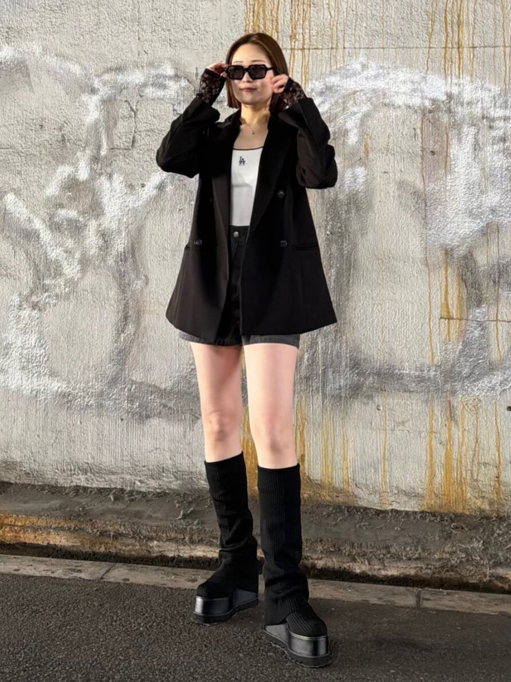 ブラック系のテーラードジャケット、ブラック系のパーカー、ホワイト系のキャミソールを着用したレディースの春コーディネートの2枚目の写真