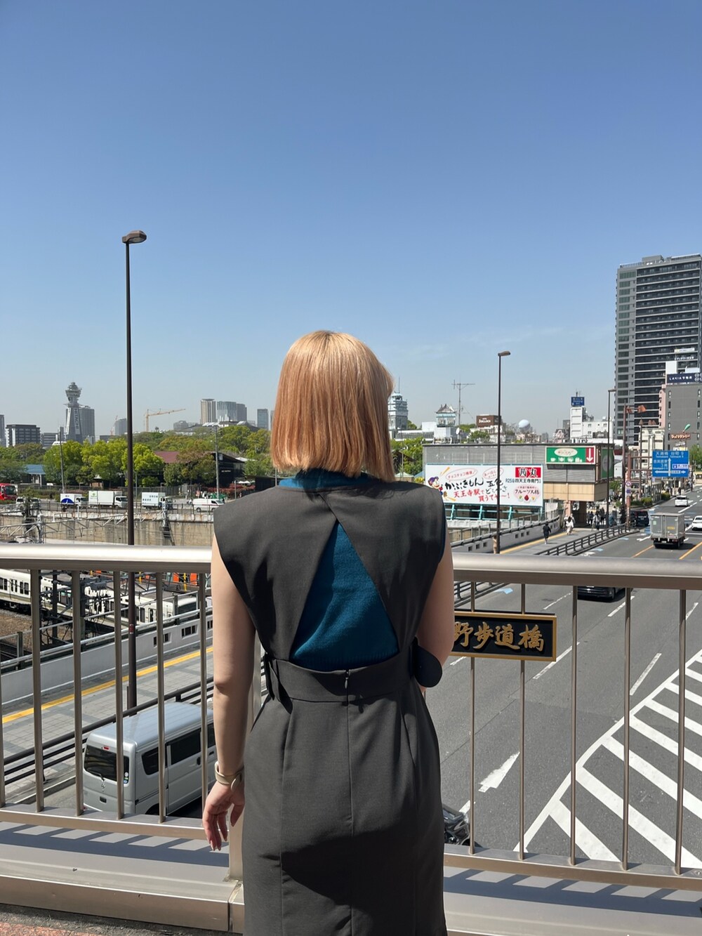 ブルー系のニット/セーター、グレー系のジャンパースカート、ホワイト系のハンドバッグを着用したレディースの春コーディネートの3枚目の写真