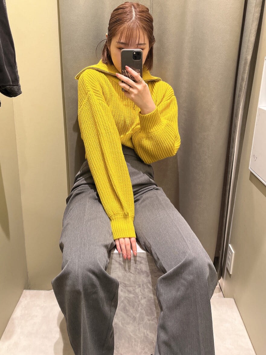 イエロー系のニット/セーター、ブラック系のブーツ、グレー系のスラックスを着用したレディースの秋コーディネートの2枚目の写真