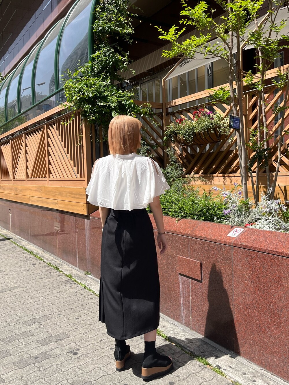 ホワイト系のシャツ/ブラウス、ブラック系のスカート、ブラック系のブーツを着用したレディースの春コーディネートの5枚目の写真