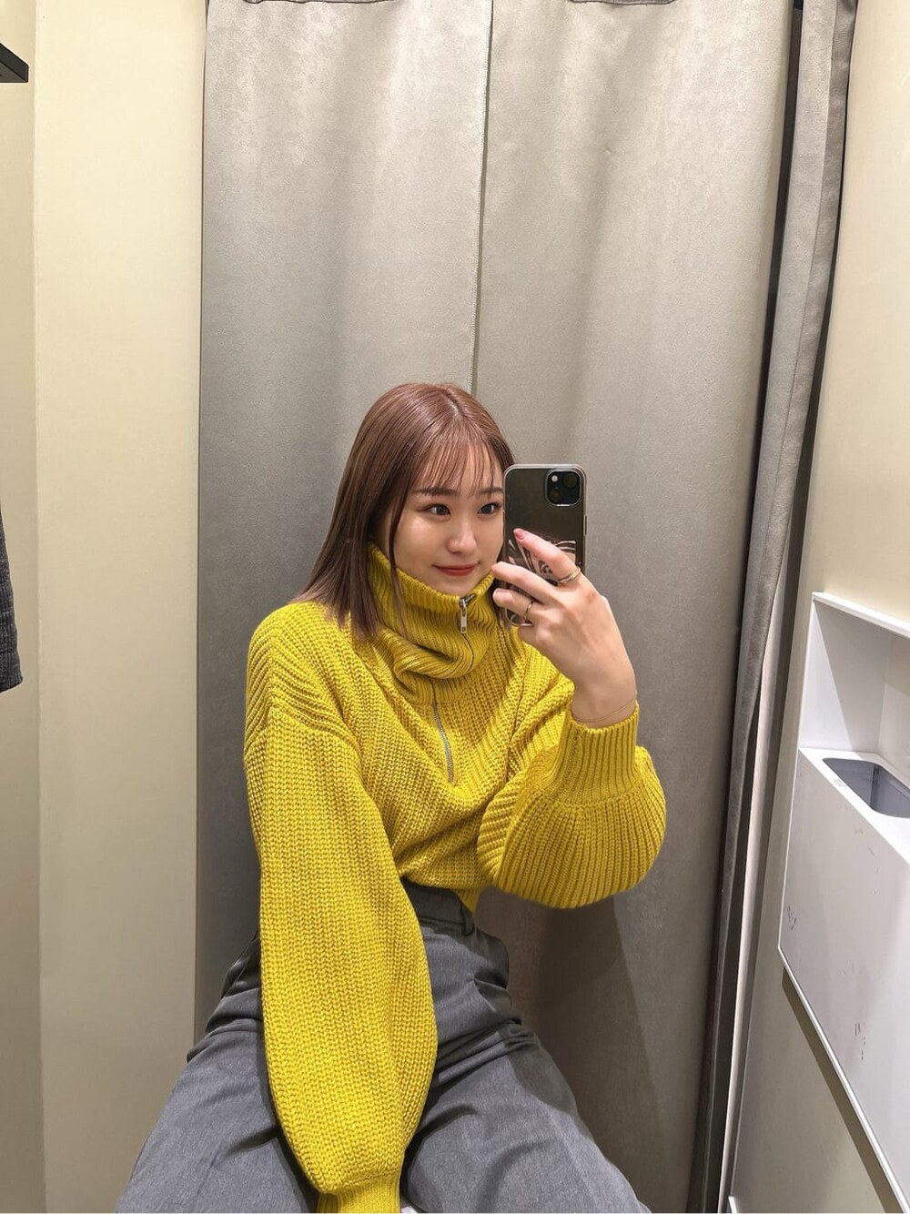 イエロー系のニット/セーター、ブラック系のブーツ、グレー系のスラックスを着用したレディースの秋コーディネートの6枚目の写真