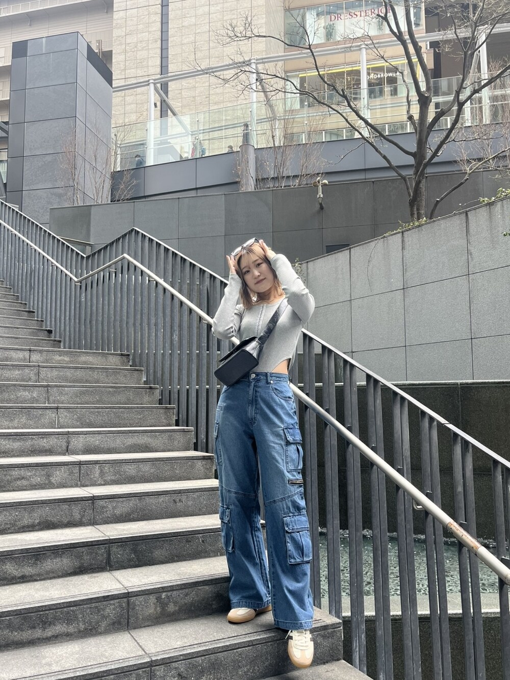 ブルー系のデニムパンツ、グレー系のTシャツ/カットソー、ブラック系のショルダーバッグを着用したレディースの春コーディネートの3枚目の写真