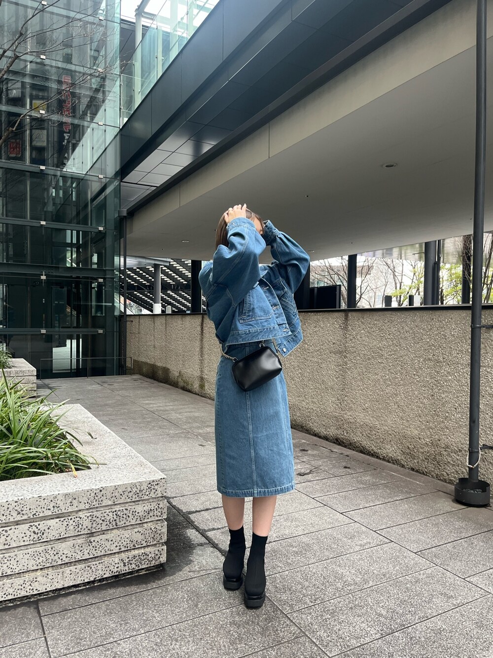 ブルー系のデニムジャケット、ブルー系のワンピース、ブラック系のブーツを着用したレディースの冬コーディネートの4枚目の写真