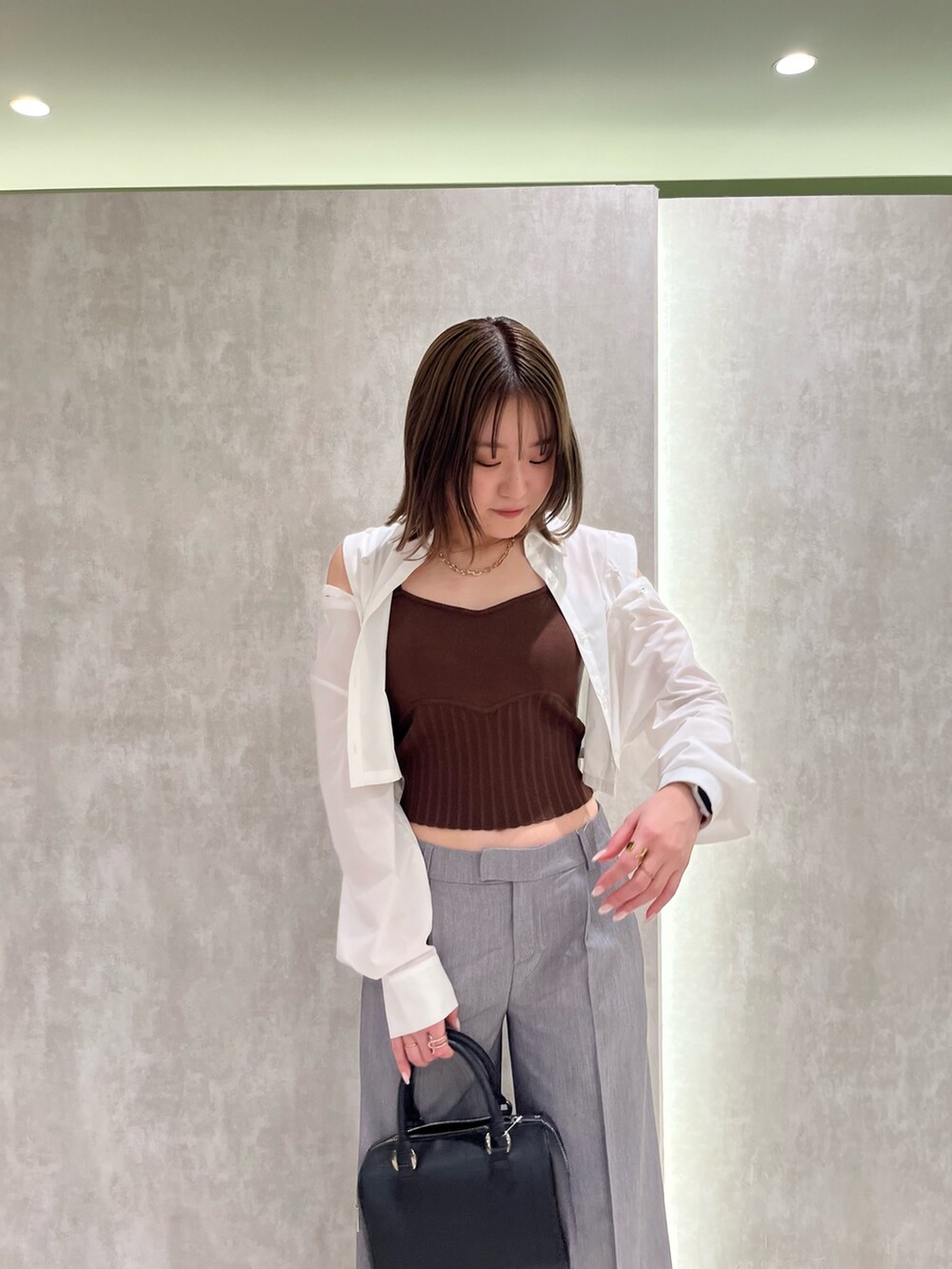 ブラウン系のニット/セーター、ホワイト系のシャツ/ブラウス、ブラック系のサンダルを着用したレディースの春コーディネートの2枚目の写真