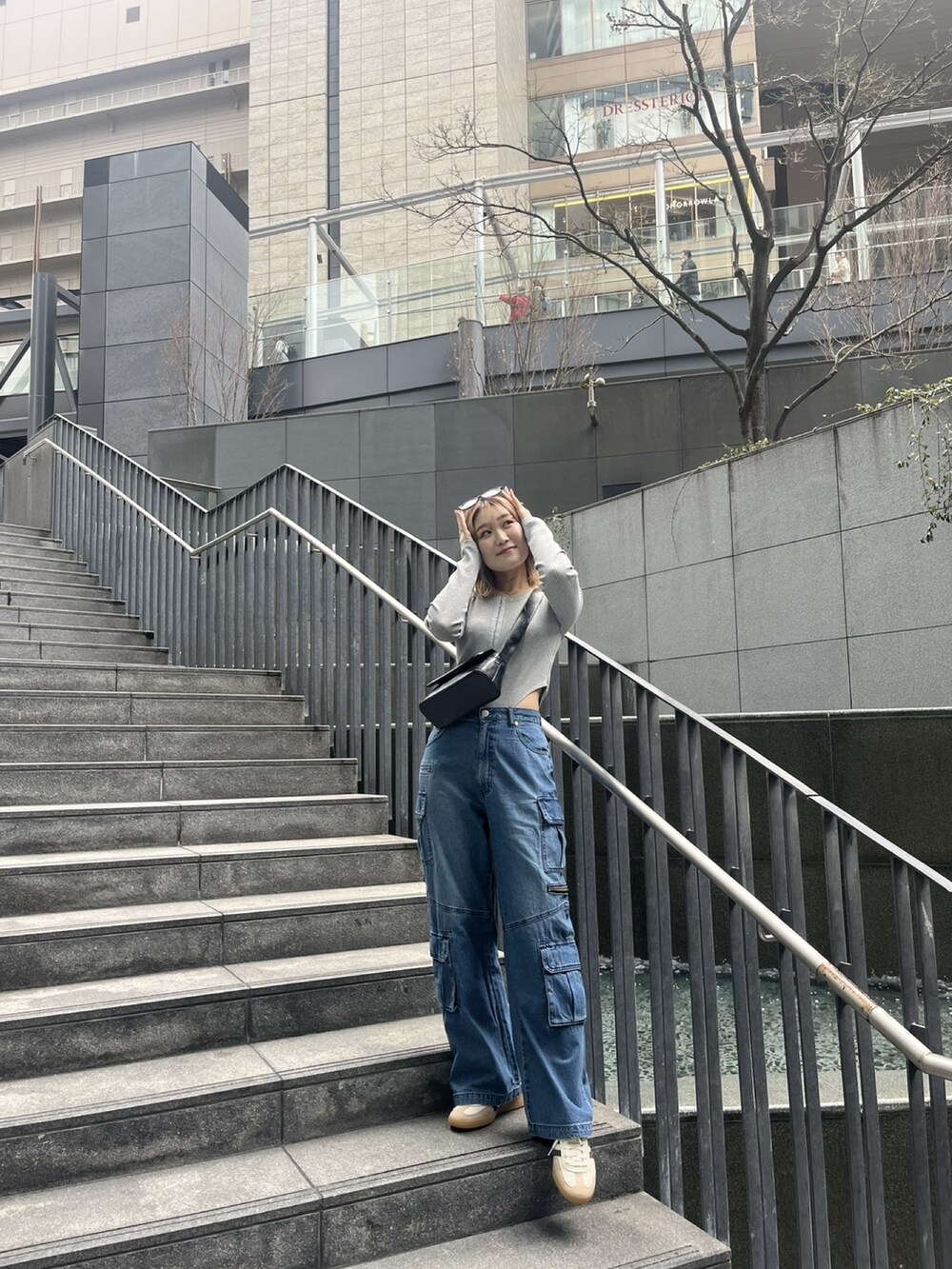 ブルー系のデニムパンツ、グレー系のTシャツ/カットソー、ブラック系のショルダーバッグを着用したレディースの春コーディネートの6枚目の写真