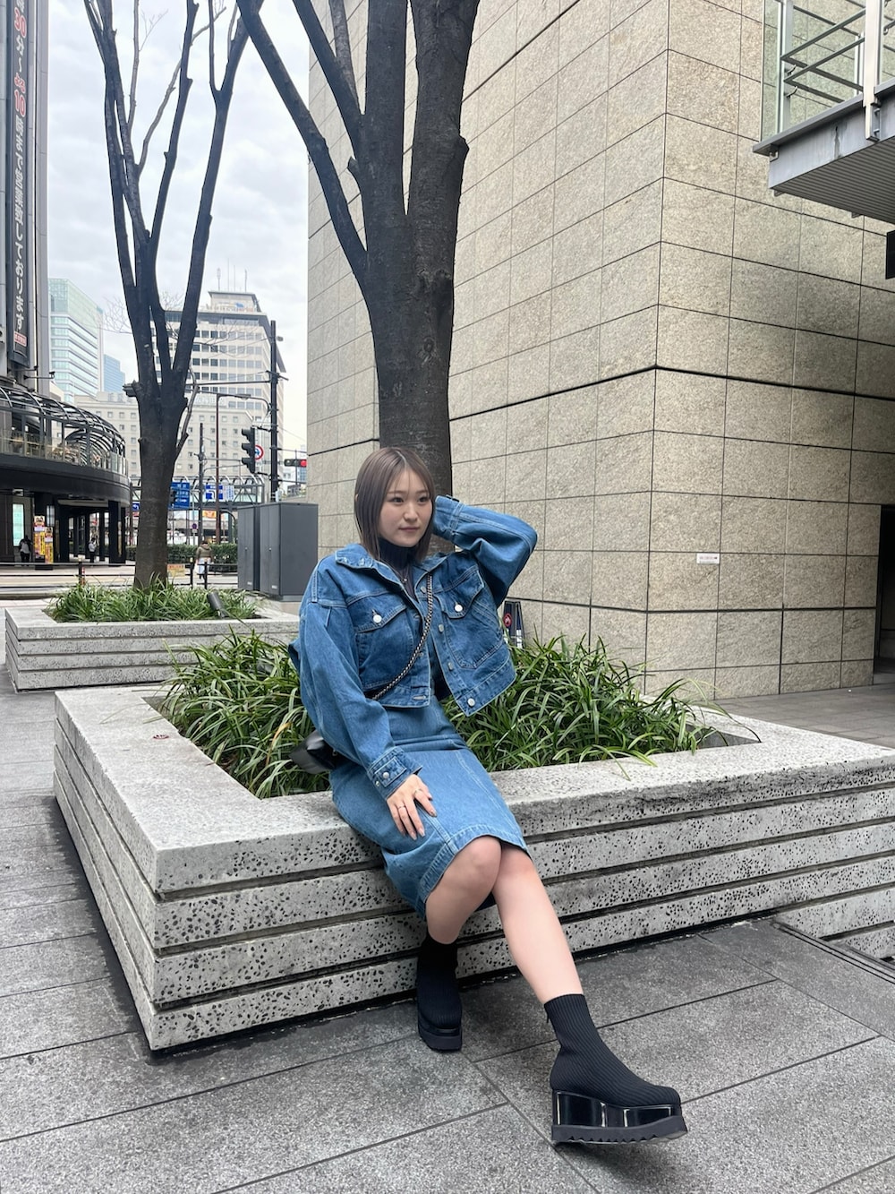 ブルー系のデニムジャケット、ブルー系のワンピース、ブラック系のブーツを着用したレディースの冬コーディネートの2枚目の写真