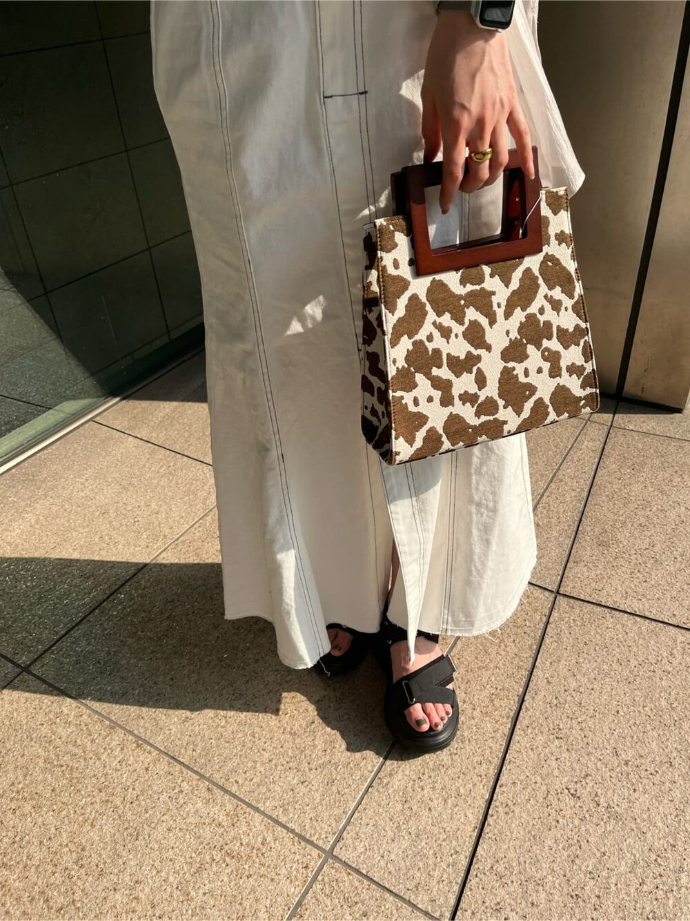 ブラック系のタンクトップ、その他のハンドバッグ、ホワイト系のデニムスカートを着用したレディースの春コーディネートの7枚目の写真