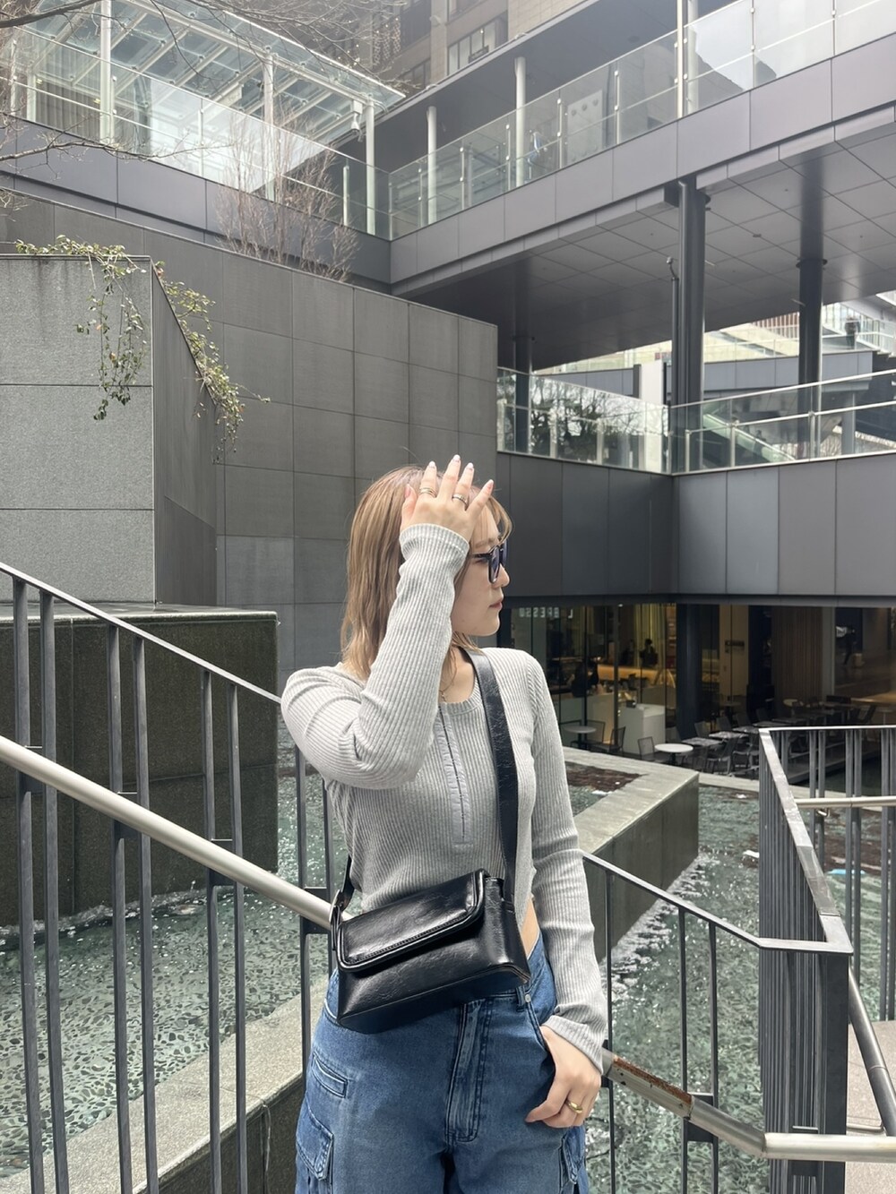 ブルー系のデニムパンツ、グレー系のTシャツ/カットソー、ブラック系のショルダーバッグを着用したレディースの春コーディネートの4枚目の写真