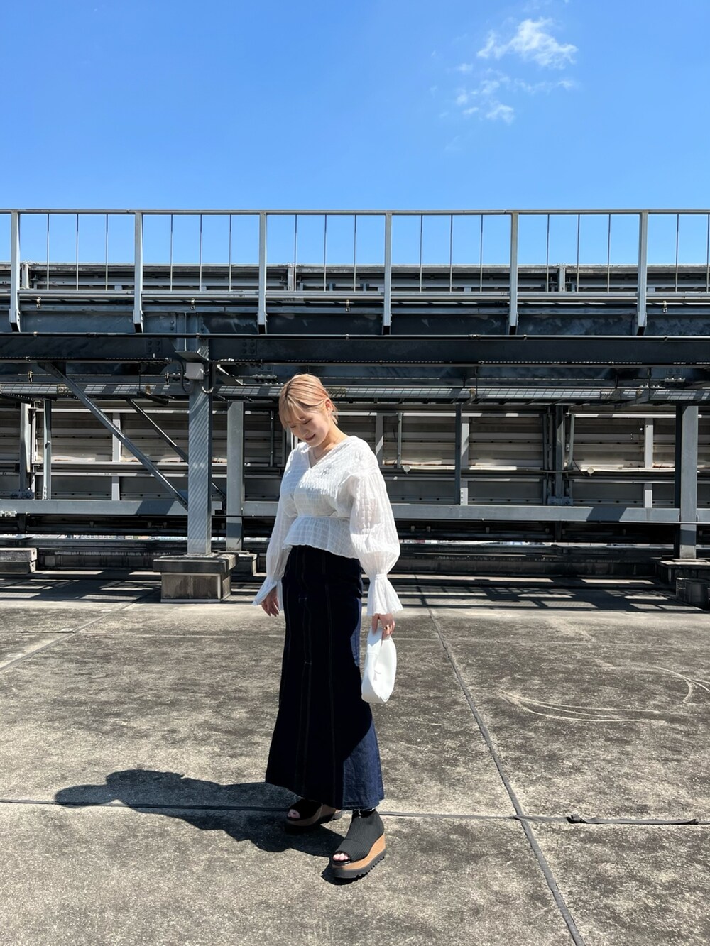 ホワイト系のシャツ/ブラウス、ホワイト系のハンドバッグ、ブラック系のブーツを着用したレディースの春コーディネートの4枚目の写真