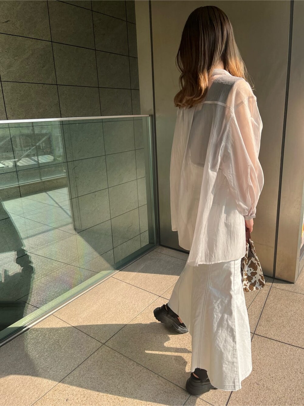 ブラック系のタンクトップ、その他のハンドバッグ、ホワイト系のデニムスカートを着用したレディースの春コーディネートの2枚目の写真