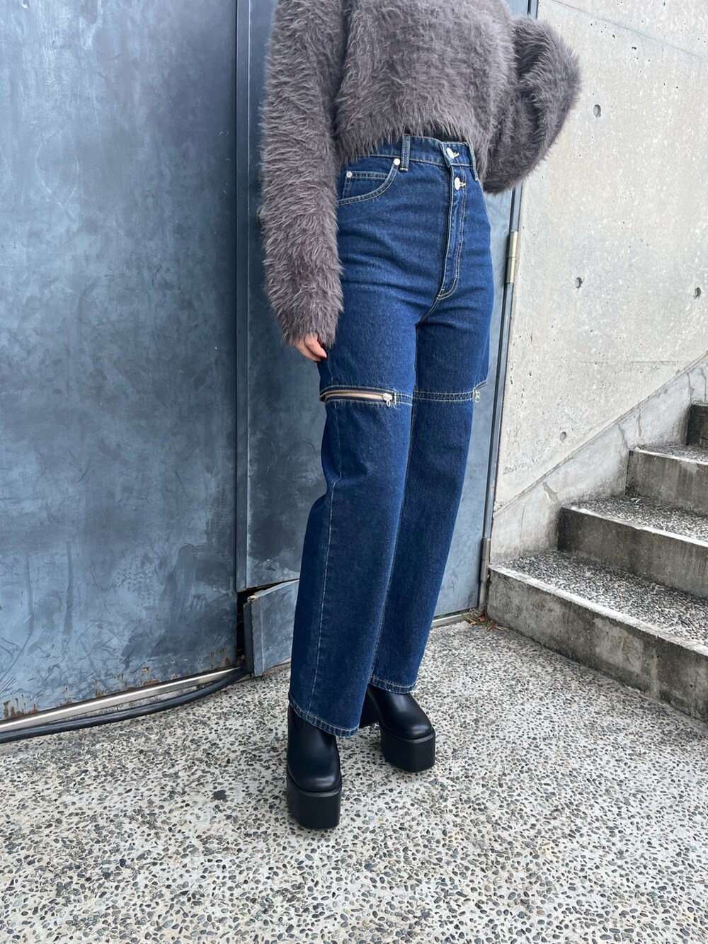 グレー系のニット/セーター、ブルー系のデニムパンツ、ブラック系のブーツを着用したレディースの秋コーディネートの4枚目の写真