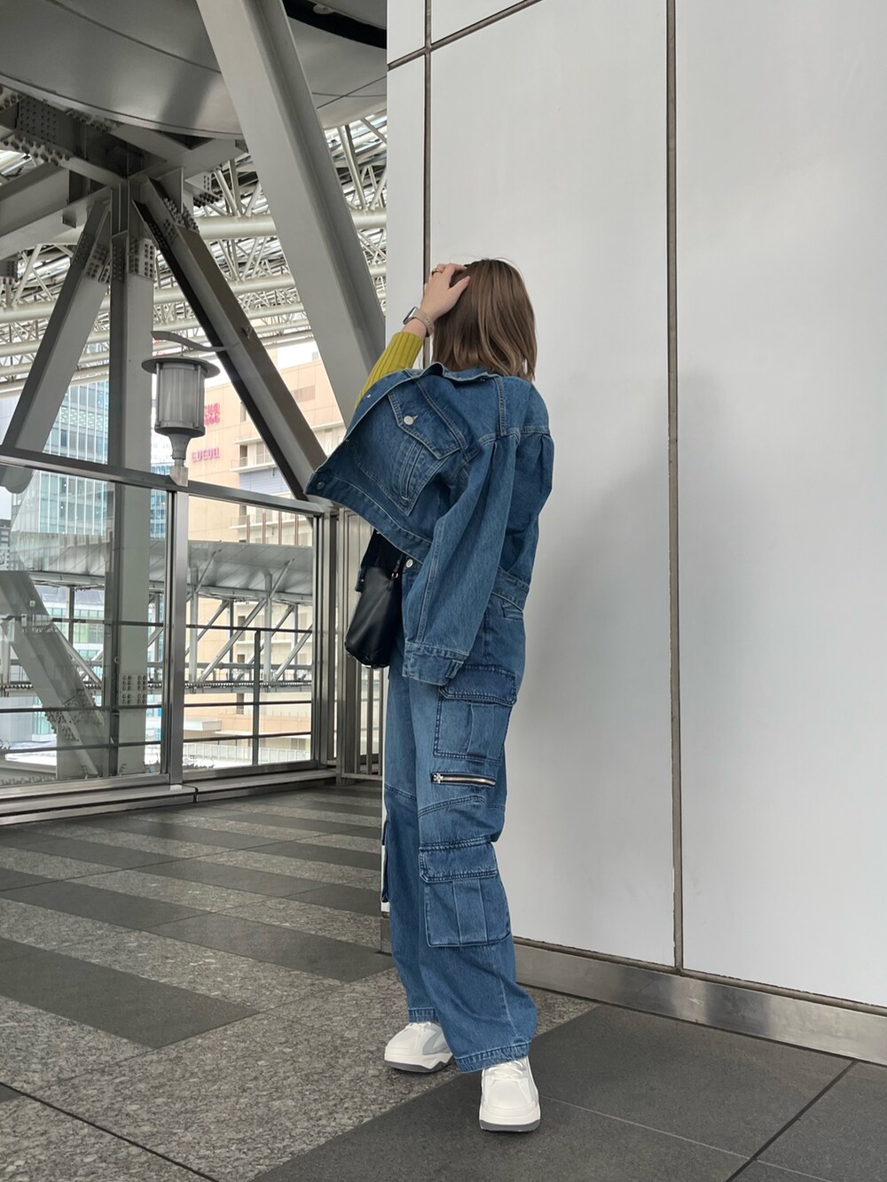 グリーン系のニット/セーター、ブルー系のデニムパンツ、グレー系のスニーカーを着用したレディースの冬コーディネートの3枚目の写真