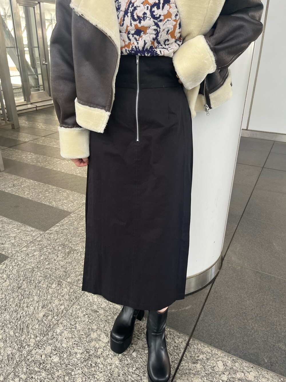 パープル系のニット/セーター、ブラック系のスカート、ブラック系のブーツを着用したレディースの秋コーディネートの6枚目の写真