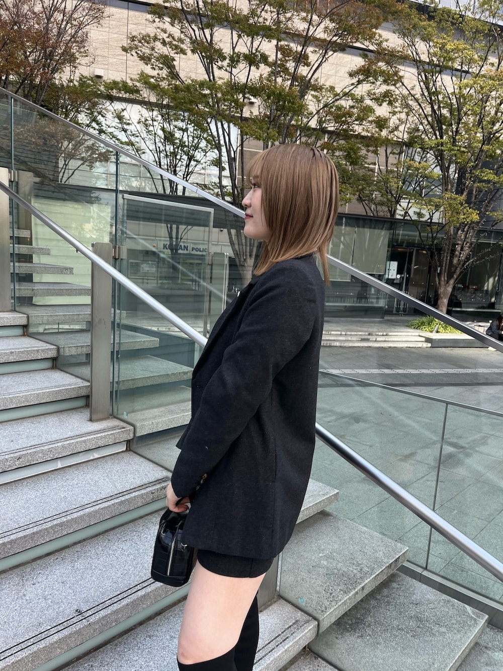 グレー系のテーラードジャケット、ホワイト系のニット/セーター、グレー系のスカートを着用したレディースの秋コーディネートの5枚目の写真