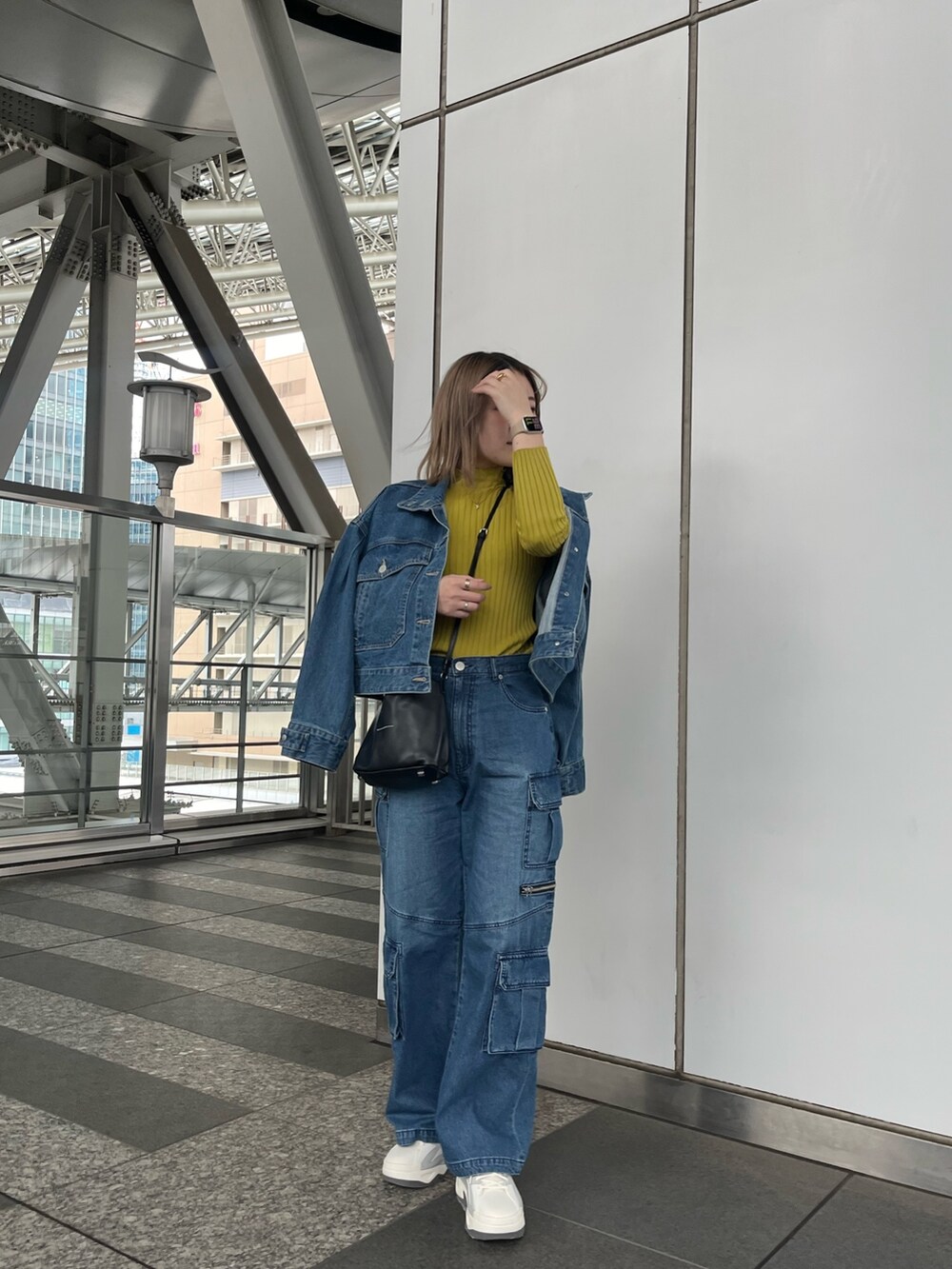 グリーン系のニット/セーター、ブルー系のデニムパンツ、グレー系のスニーカーを着用したレディースの冬コーディネートの2枚目の写真