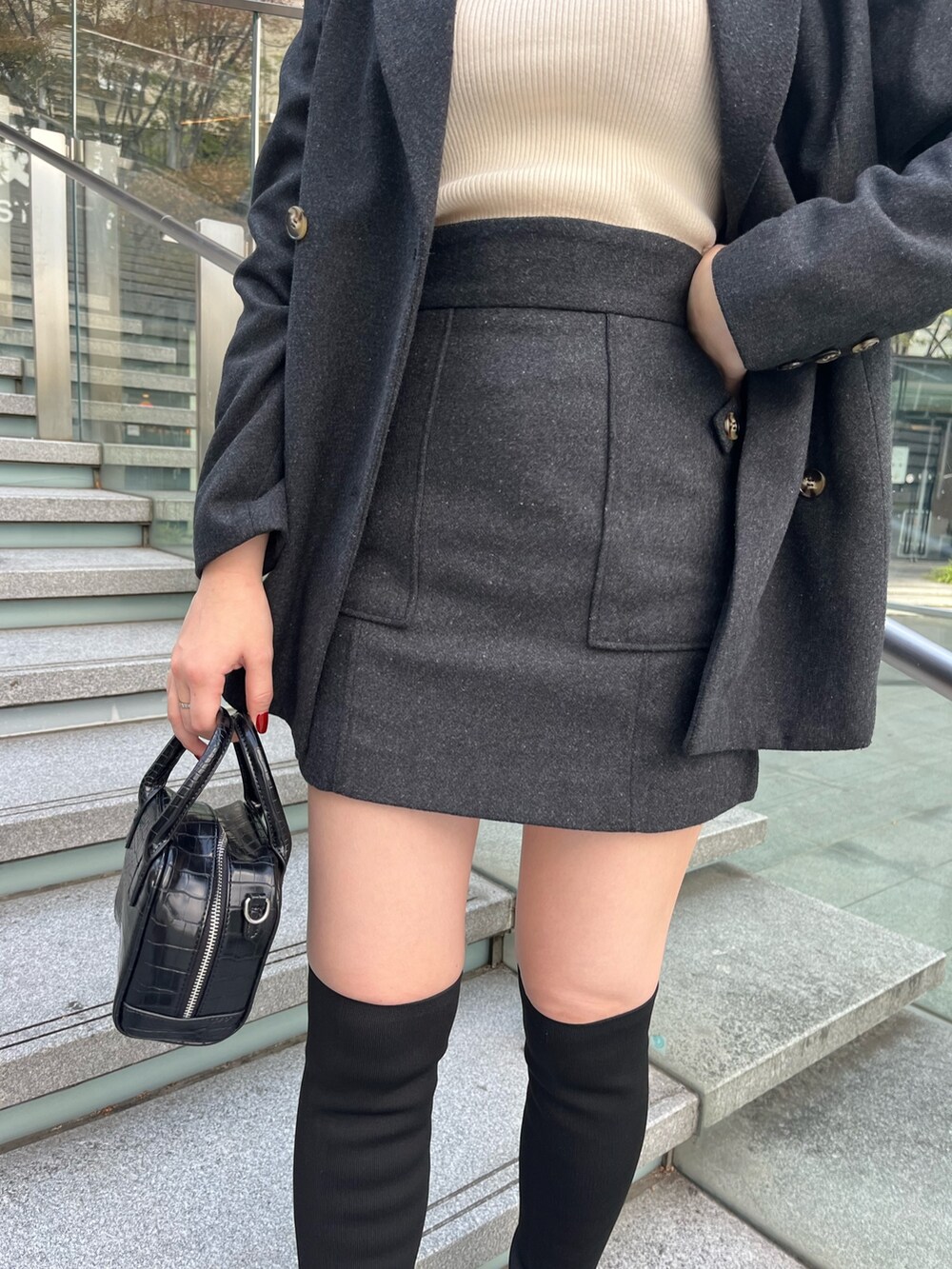 グレー系のテーラードジャケット、ホワイト系のニット/セーター、グレー系のスカートを着用したレディースの秋コーディネートの6枚目の写真