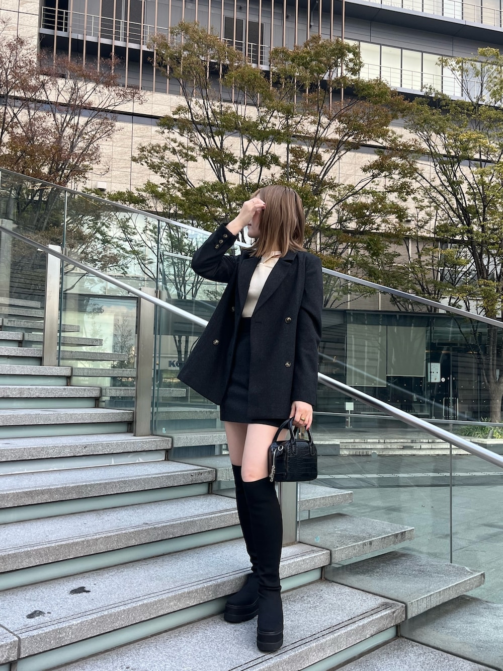 グレー系のテーラードジャケット、ホワイト系のニット/セーター、グレー系のスカートを着用したレディースの秋コーディネートの4枚目の写真