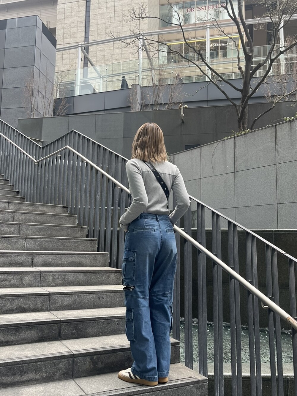 ブルー系のデニムパンツ、グレー系のTシャツ/カットソー、ブラック系のショルダーバッグを着用したレディースの春コーディネートの7枚目の写真