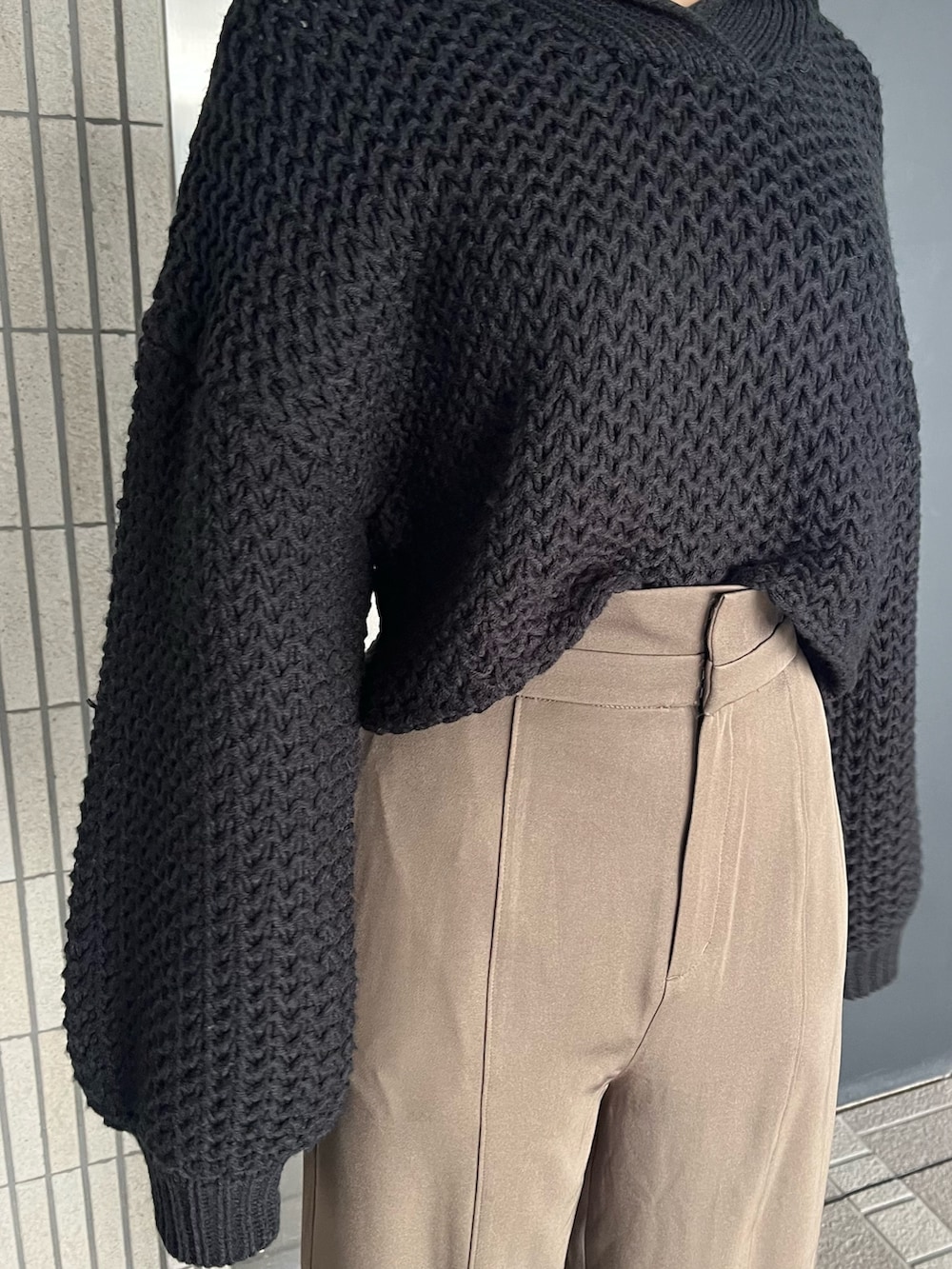 ブラック系のニット/セーター、ベージュ系のスラックス、ブラック系のブーツを着用したレディースの冬コーディネートの7枚目の写真