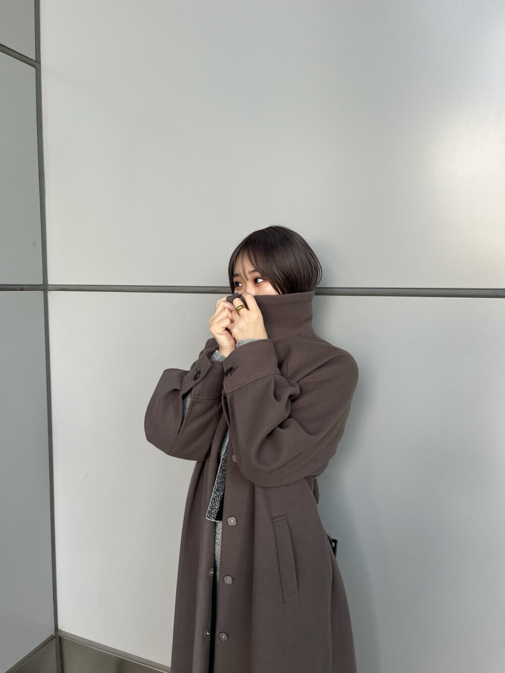 グレー系のニット/セーター、グレー系のスカート、ブラウン系のステンカラーコートを着用したレディースの冬コーディネートの6枚目の写真