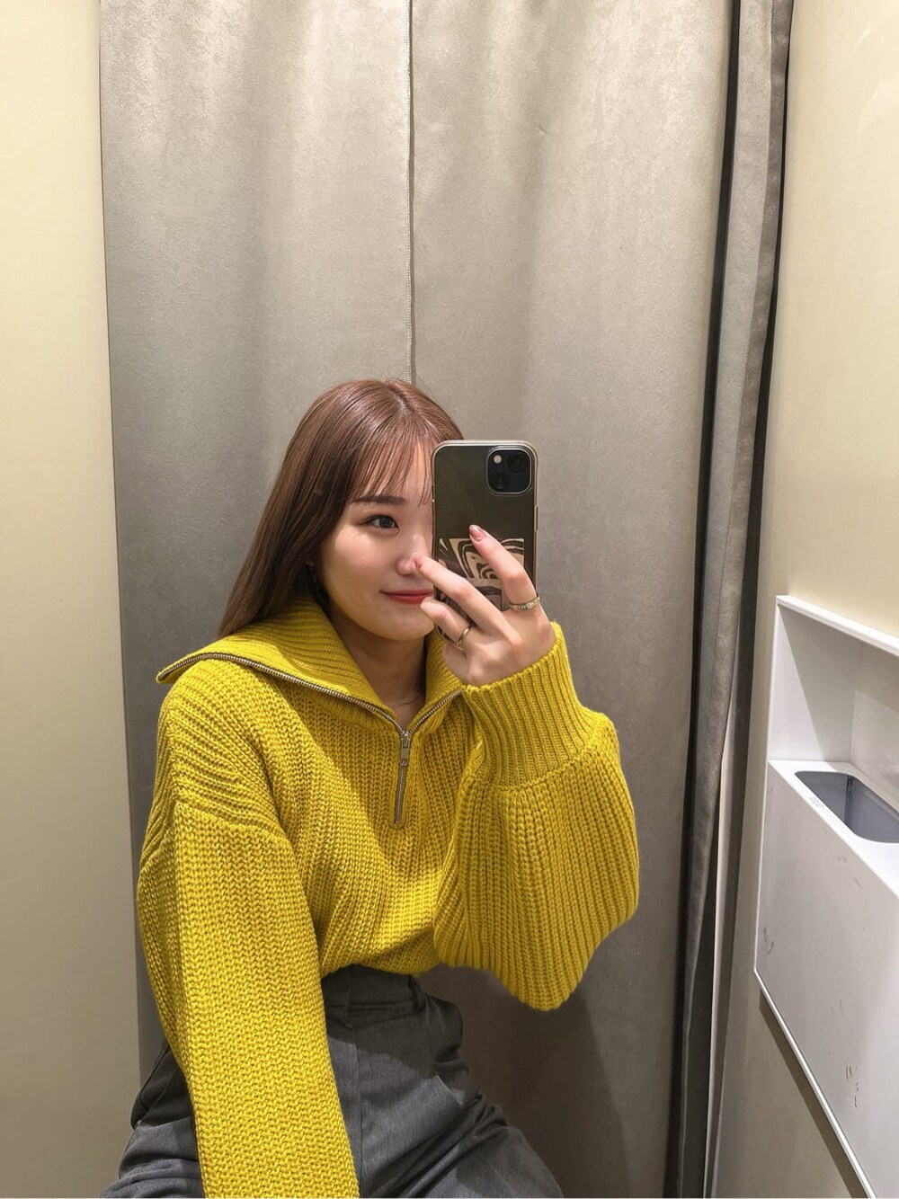 イエロー系のニット/セーター、ブラック系のブーツ、グレー系のスラックスを着用したレディースの秋コーディネートの3枚目の写真