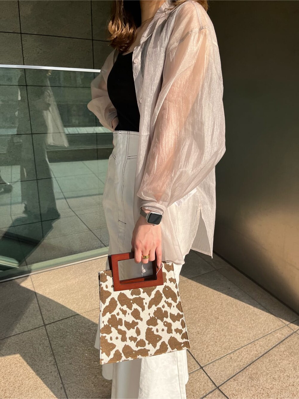 ブラック系のタンクトップ、その他のハンドバッグ、ホワイト系のデニムスカートを着用したレディースの春コーディネートの3枚目の写真