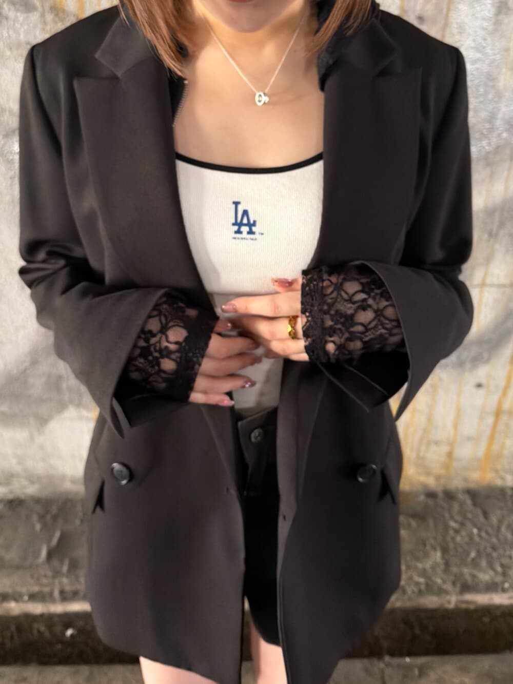 ブラック系のテーラードジャケット、ブラック系のパーカー、ホワイト系のキャミソールを着用したレディースの春コーディネートの6枚目の写真