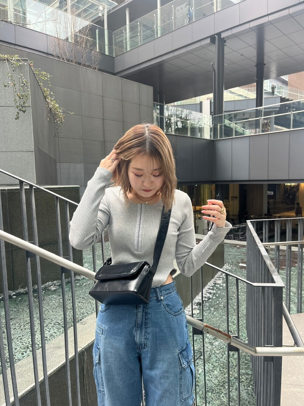 ブルー系のデニムパンツ、グレー系のTシャツ/カットソー、ブラック系のショルダーバッグを着用したレディースの春コーディネートの5枚目の写真