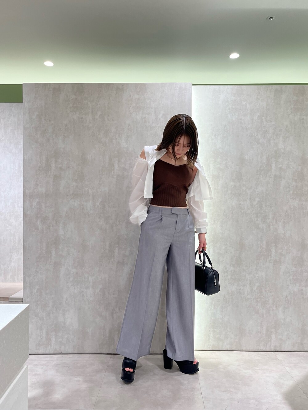 ブラウン系のニット/セーター、ホワイト系のシャツ/ブラウス、ブラック系のサンダルを着用したレディースの春コーディネートの7枚目の写真