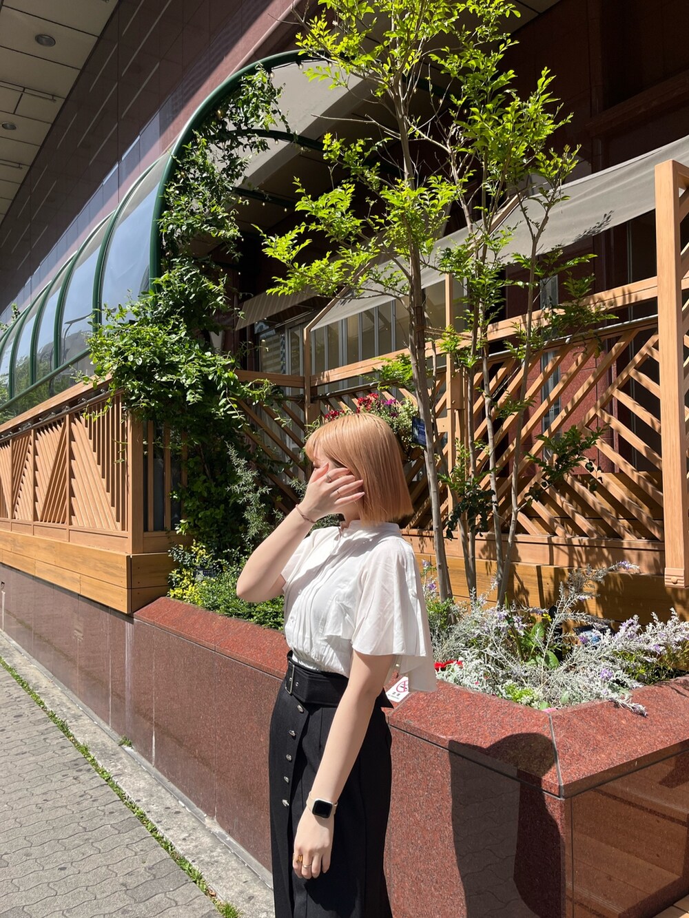 ホワイト系のシャツ/ブラウス、ブラック系のスカート、ブラック系のブーツを着用したレディースの春コーディネートの3枚目の写真